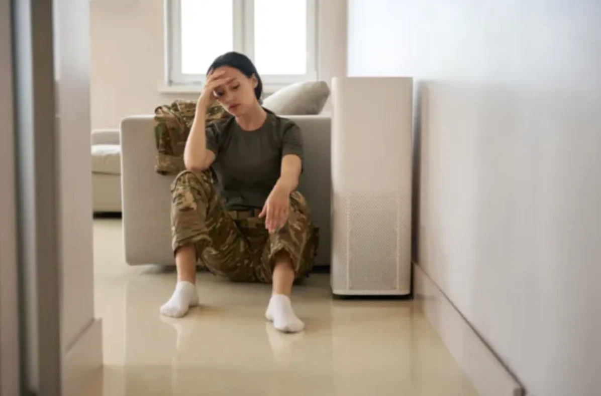 upset young female veteran sitting on the floor